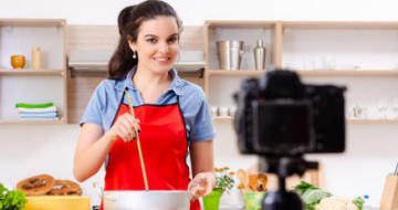 Lady cooking in the kitchen recording video using her phone